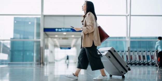 A person walking with a luggage bag AI-generated content may be incorrect.